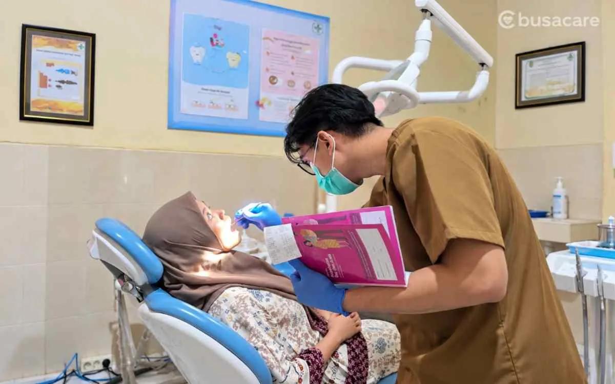 Dokter gigi memeriksa kesehatan gigi dan mulut pasien perempuan di klinik untuk mendukung perawatan gigi secara rutin.