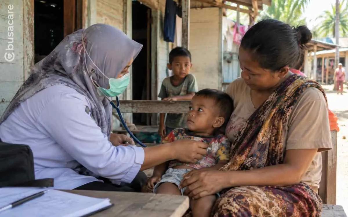 Tenaga kesehatan memeriksa balita yang didampingi ibunya sebagai gambaran pentingnya akses layanan kesehatan bagi masyarakat kurang mampu.