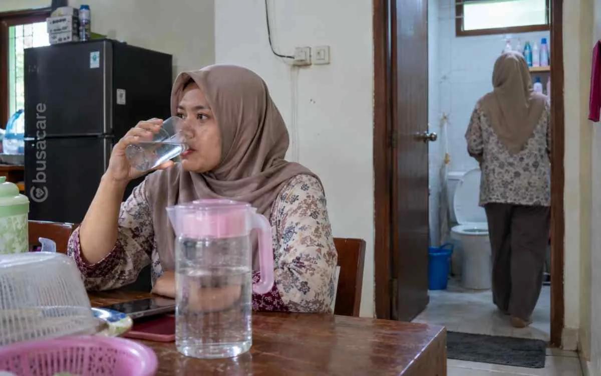 Perempuan minum air putih di rumah sebagai ilustrasi gejala sering haus dan kerap buang air kecil yang dapat berkaitan dengan diabetes.